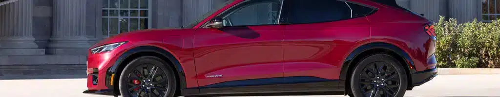 Red electric SUV parked in front of a classical building with prominent columns.