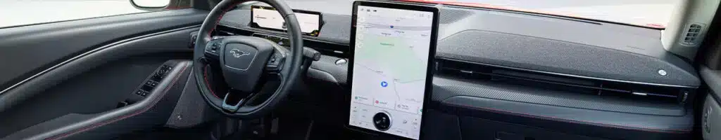 Interior of a car featuring a modern steering wheel and large touchscreen navigation display.