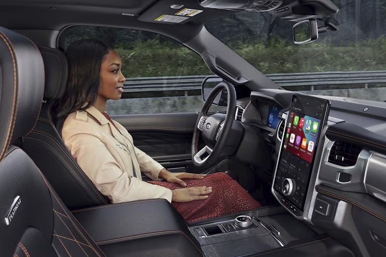Woman inside a modern car interior with a large touchscreen display showing apps.