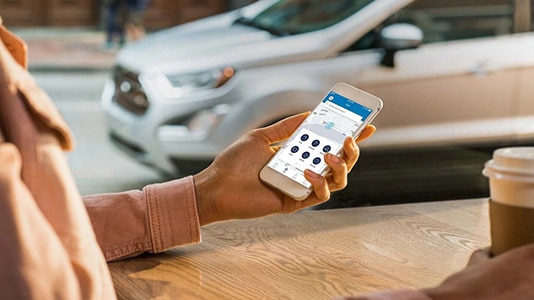 Person using a smartphone app, with a parked SUV visible through a window.