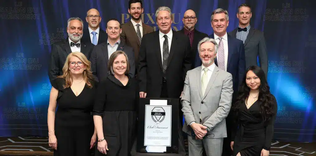 Group of well-dressed individuals posing at an award ceremony, with a framed certificate displayed.
