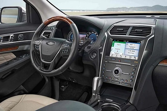 Modern car interior with touchscreen navigation display, leather steering wheel, and control panel.