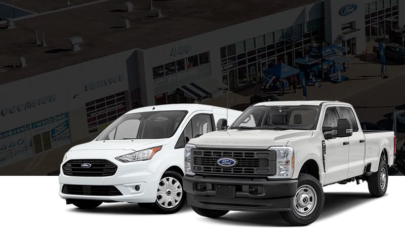 Deux véhicules Ford blancs, un utilitaire et un pick-up, sont stationnés devant un concessionnaire automobile.