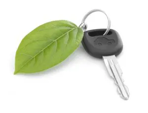 Clé de voiture avec feuille verte sur fond blanc, symbolisant l'écologie et l'automobile durable.