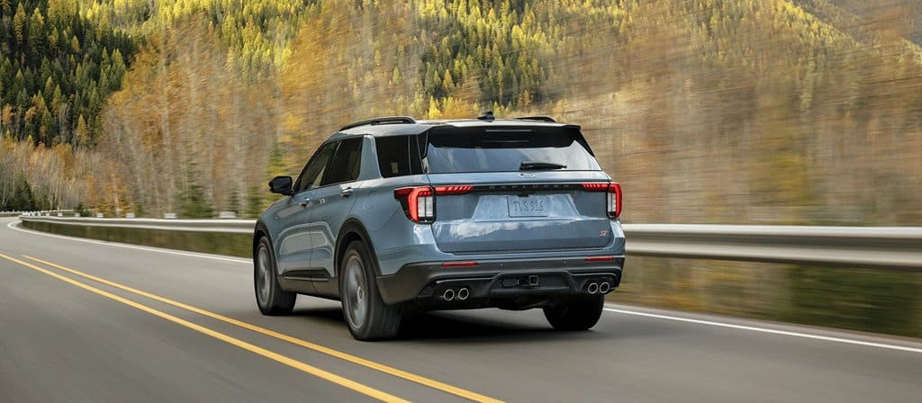 Ford Explorer 2026, vue arrière sur une route bordée de forêt